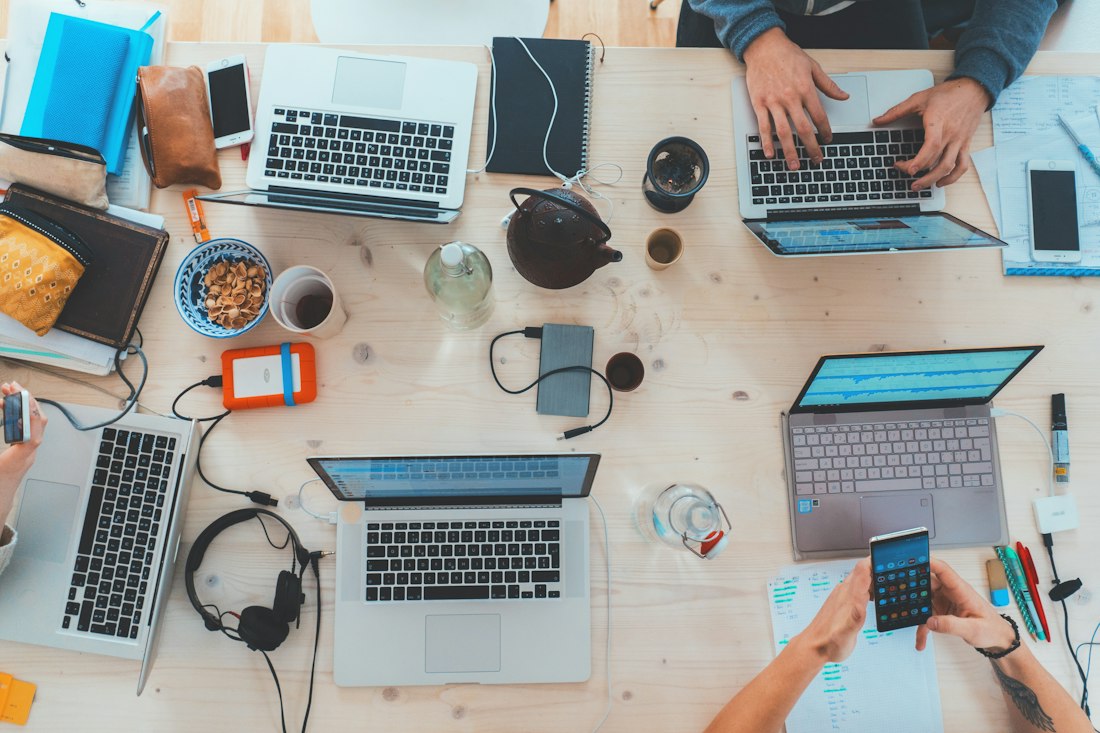 A small startup team working through plans on laptops in a shared workspace